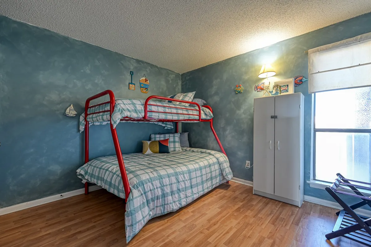 A cheerful guest bedroom is showcased here, with a twin-over-full bunk bed, colorful wall decorations, and a wardrobe. The space feels playful and welcoming, perfect for children or groups of friends.